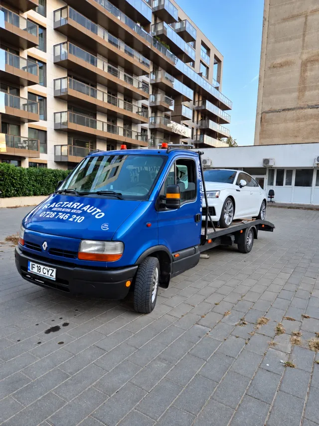 Platformă auto albastră cu o mașină albă încărcată
